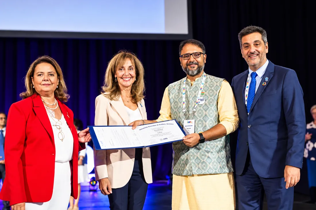 Dr. Sanchit Paul receiving a certificate on stage at an International Association of Paediatric Dentistry congress