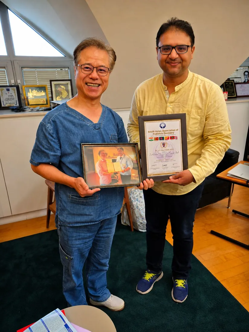 Dr. Sanchit Paul holding the framed South Asian Association of Pediatric Dentistry award certificate